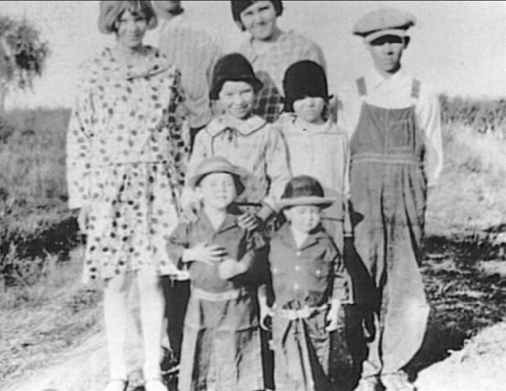 Black-and-white photograph of Audie Murphy as a young boy standing with his siblings in rural Texas.